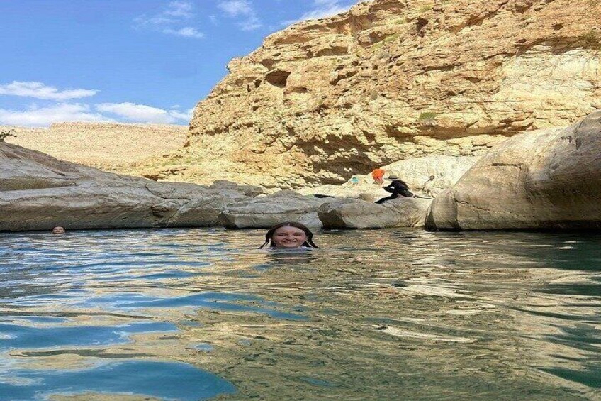 Una persona nuota in una piscina limpida, con scogliere rocciose sullo sfondo. 2