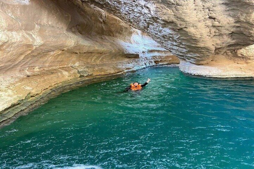 Una persona che galleggia in una piscina turchese, circondata da scogliere rocciose. 4