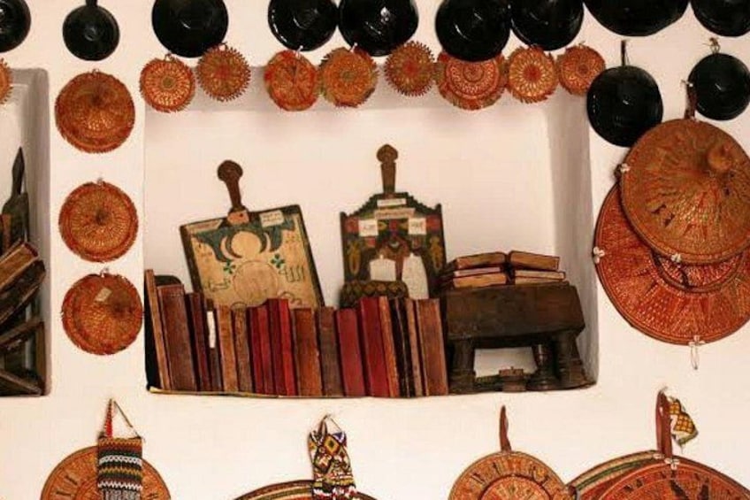 A collection of woven baskets, books, and a small wooden structure against a white wall. 5