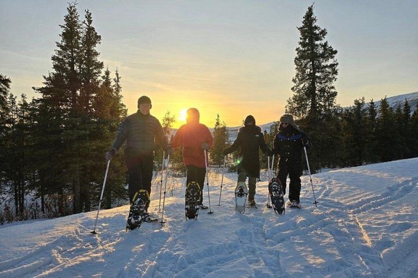 Skiers on a snowy slope with the sun setting in the background. 2