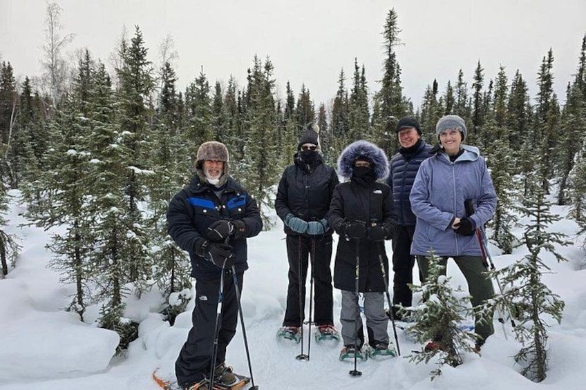 A group of people in a snowy forest with trees and snow-covered ground. 4