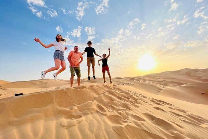 A group of people jumping on sand dunes at sunset. 1