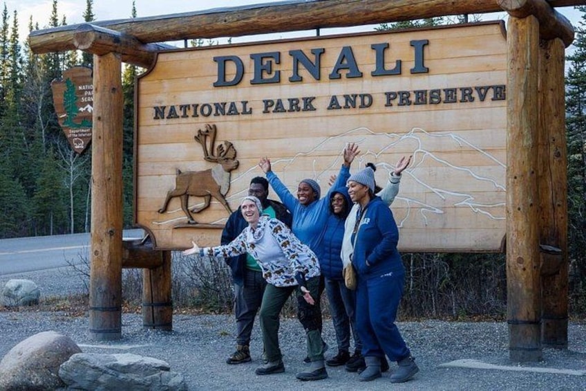 Un letrero de madera con el texto 'DENALI NATIONAL PARK AND PRESERVE' e ilustraciones de fauna. 1
