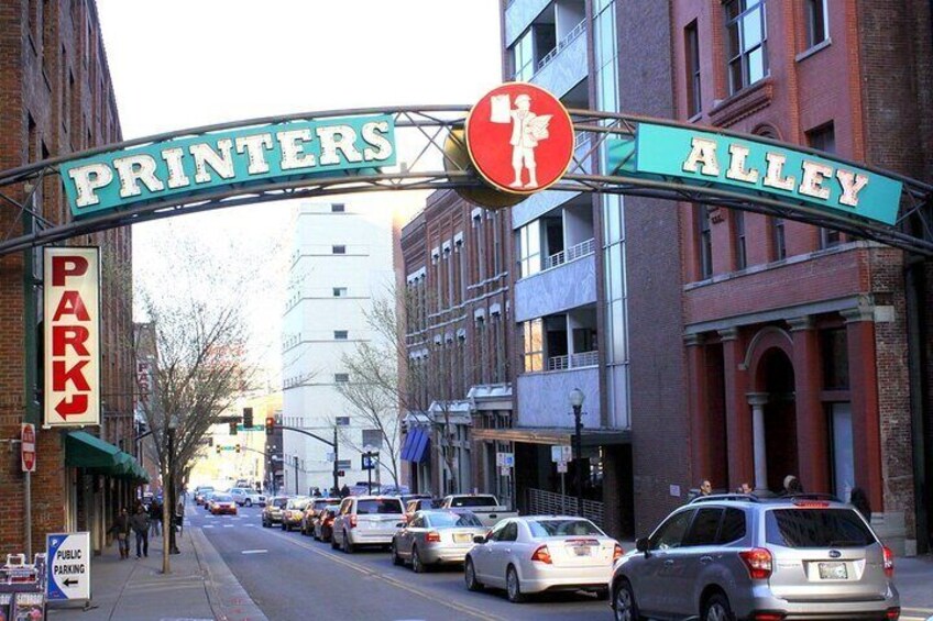 En gade med parkerede biler og et skilt, der siger "Printers Alley". 2