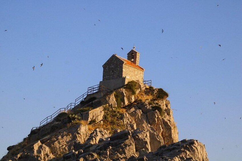 Una iglesia de piedra sobre un acantilado rocoso, con cielo despejado. 2