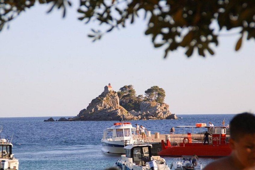 Paisaje costero con barcos, una isla rocosa y cielo despejado. 1