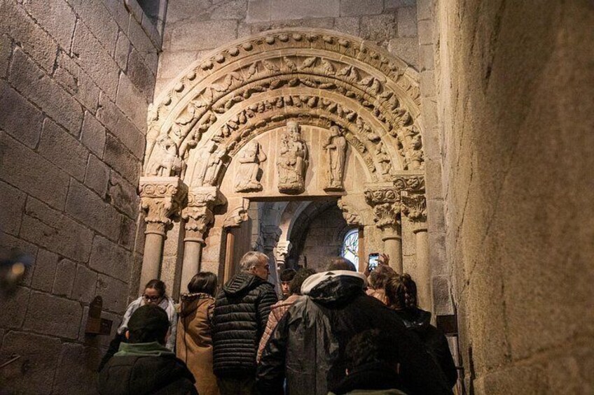 Un grupo de personas caminando por un estrecho pasillo de piedra con un arco gótico decorado. 2