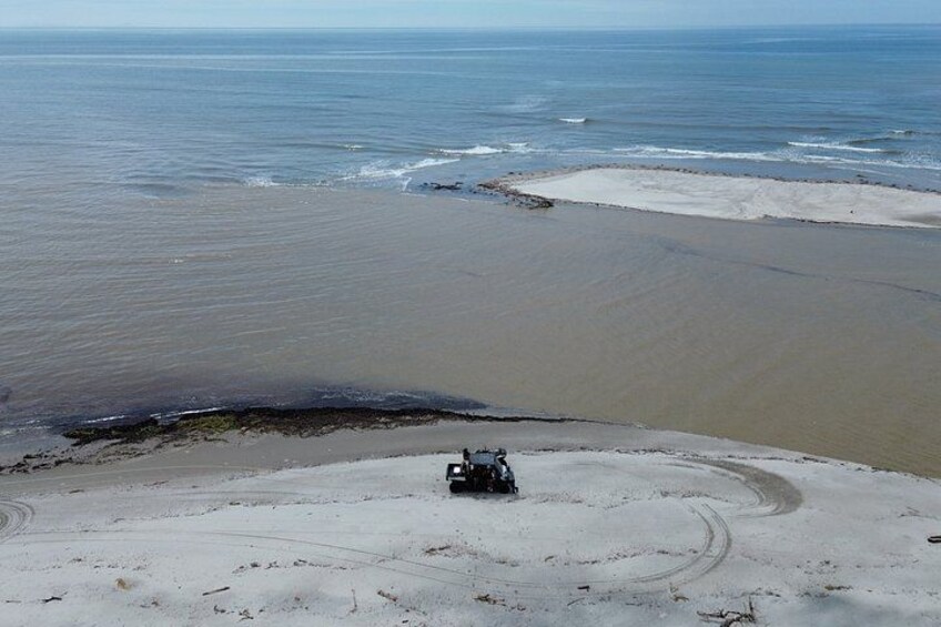 A vehicle on a sandy beach with a body of water in the background. 5