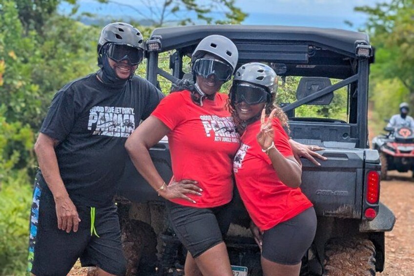 Three people in red shirts posing with a black off-road vehicle. 2