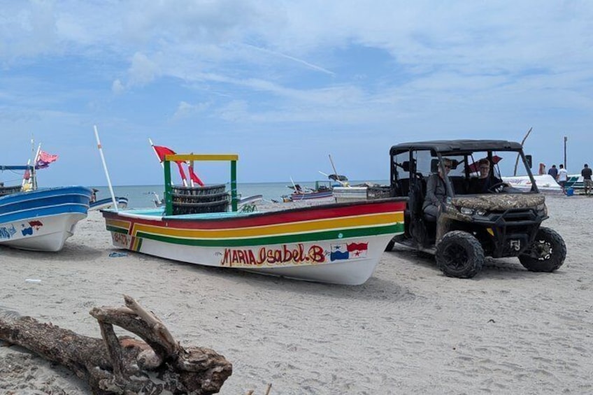 A beach with boats and a 4x4 vehicle. 1