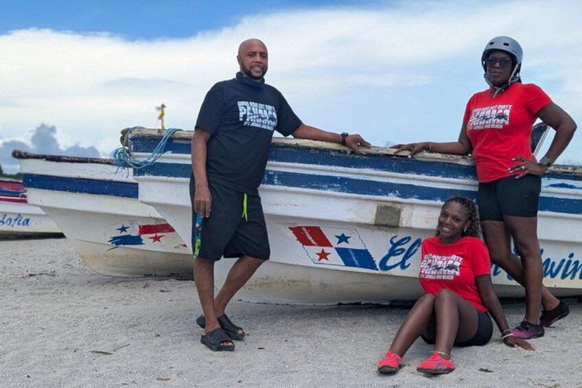 Three people standing and sitting near a boat with 'Elwin' written on it. 4