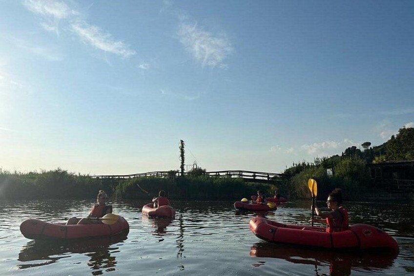 People kayaking on a calm river with a bridge in the background. 2