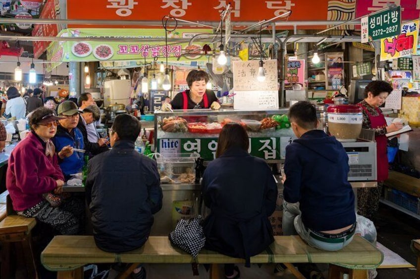 A bustling street food market with people dining at outdoor tables. 3