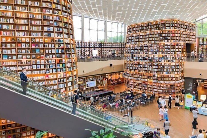 A modern library with large spiral bookshelves and a central open space with tables and chairs. 2