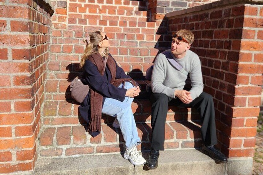 Two people sitting on a brick wall. 3