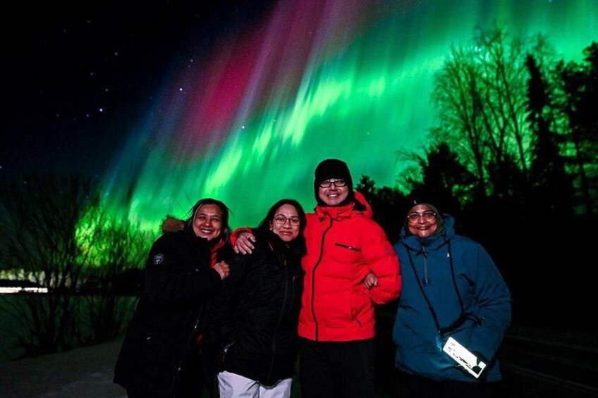 Four people posing with the Northern Lights in the background. 2