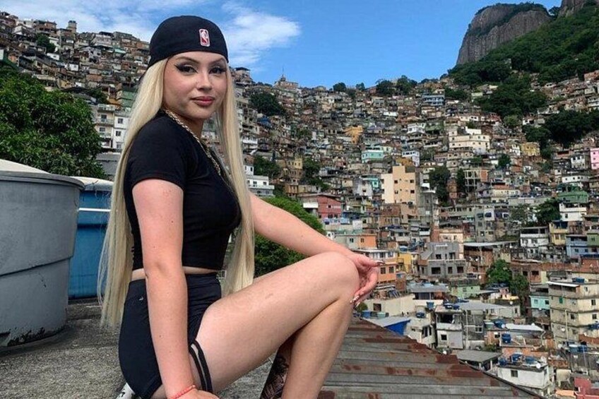 A person sitting on a rooftop with a densely packed urban landscape in the background. 1