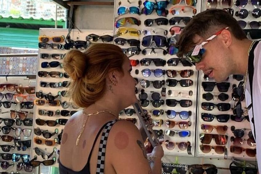 A person examining sunglasses in a store with a wall of various sunglasses. 2