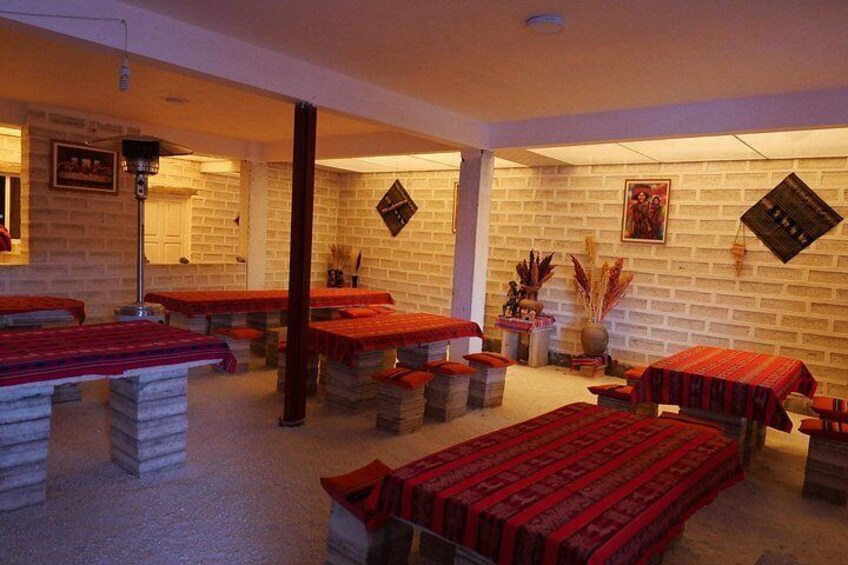 A room with multiple massage tables covered with red blankets, a brick wall, and a framed picture on the wall. 4