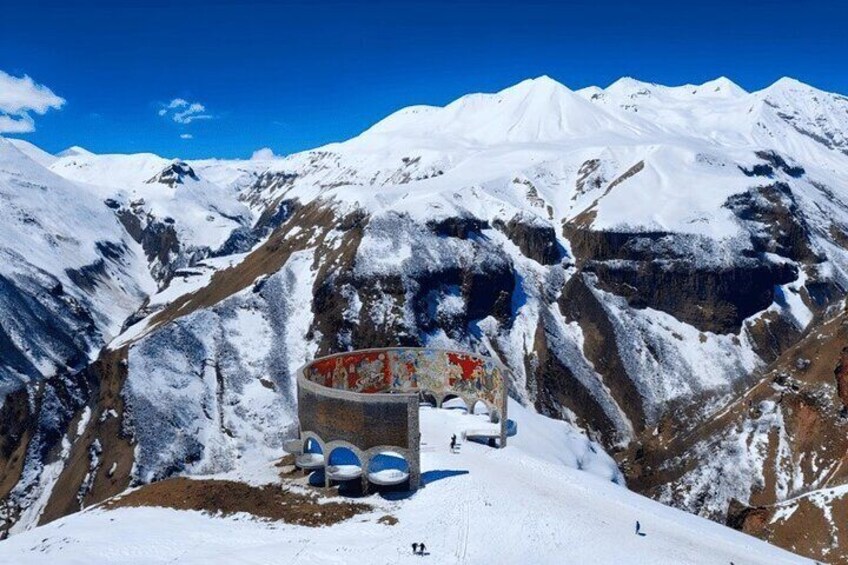 Paesaggio montano innevato con una struttura parzialmente visibile, con elementi rossi e blu. 5
