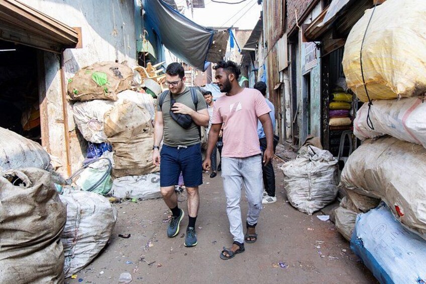 A narrow alley with people walking, surrounded by large sacks and bags. 1