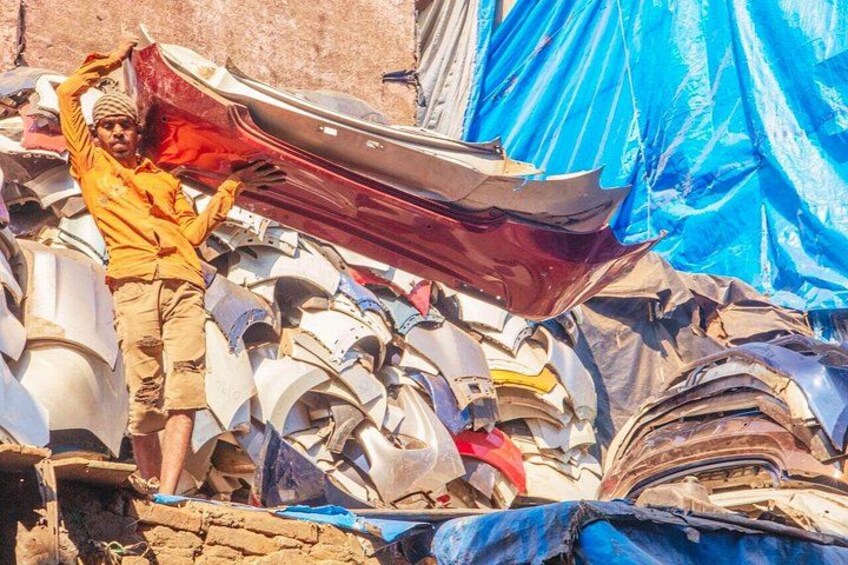 A person standing amidst a pile of discarded boat parts and metal sheets. 5