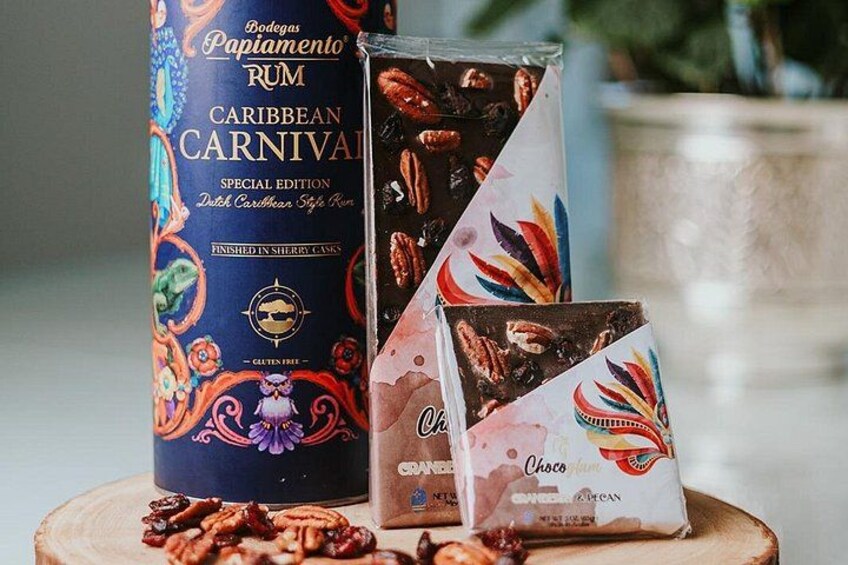A bottle of Bodega Papimento rum, a box of pecan-flavored chocolate, and a chocolate bar with a colorful design. 1