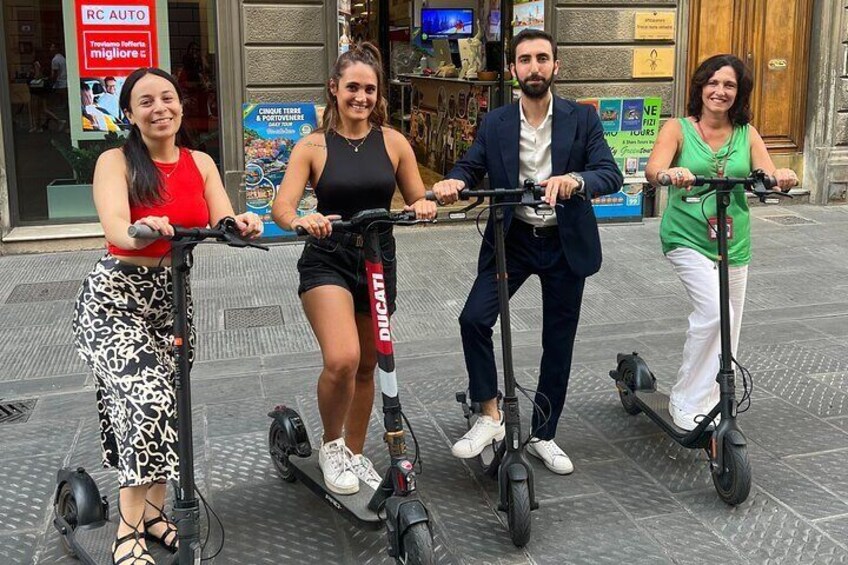 Four people riding electric scooters on a city street. 2