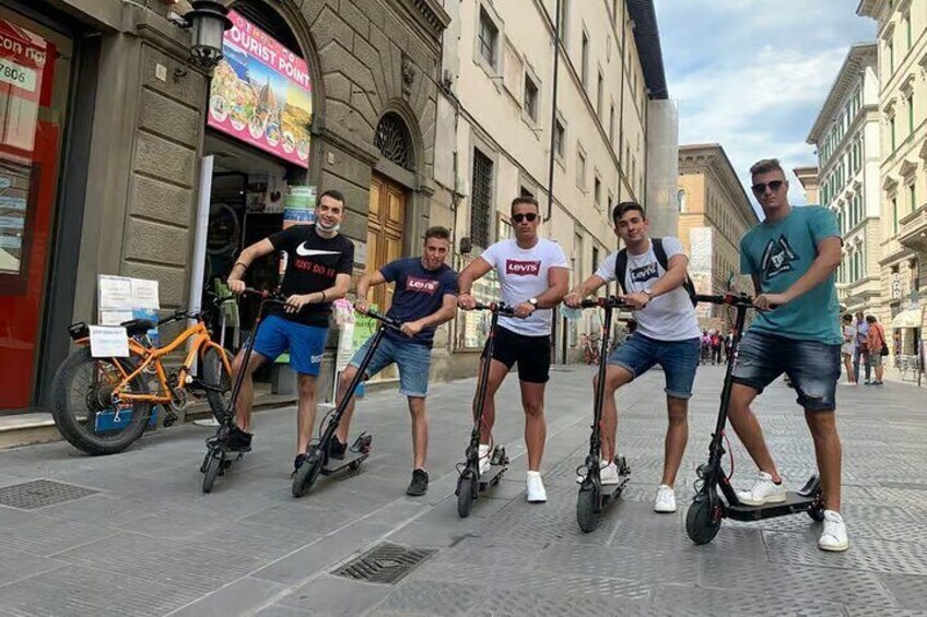 Five people riding electric scooters on a city street. 1