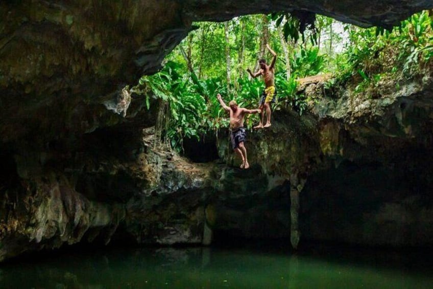 Una cueva con un estanque y personas saltando desde una roca. 3