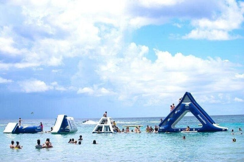 Una playa con toboganes acuáticos inflables y gente nadando. 5