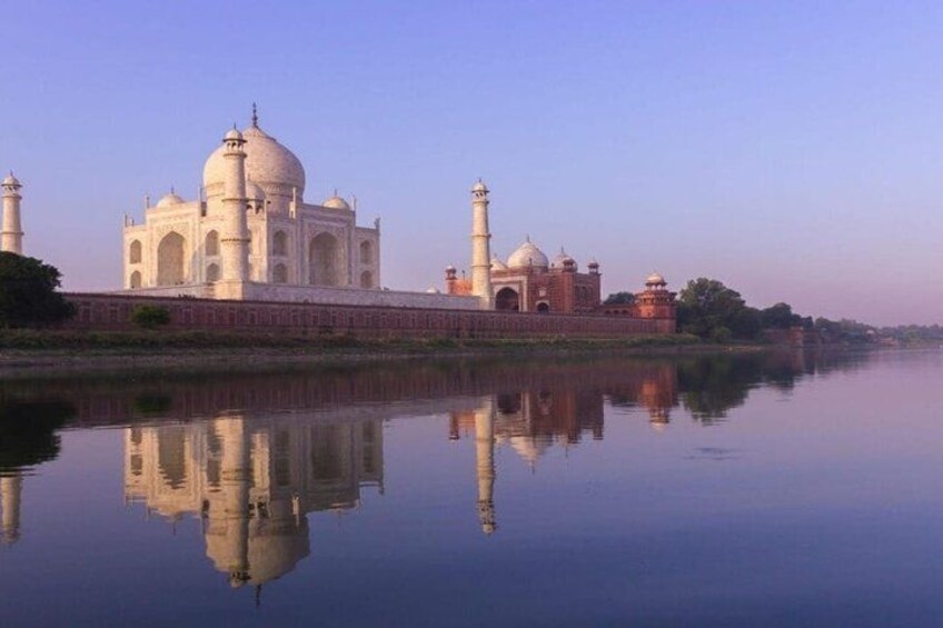 Das Taj Mahal mit seinem Spiegelbild im Wasser, einem klaren Himmel und einem ruhigen Fluss. 4
