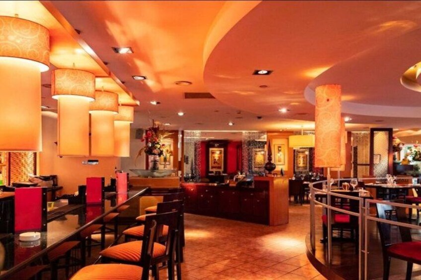 Ein Restaurantinneres mit runden Tischen, roten Stühlen und hängenden Lampen. 3