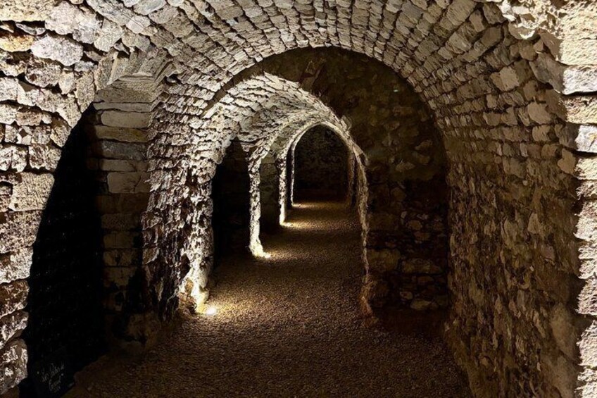 Un passage souterrain en pierre, doté de voûtes en arc et d’un étroit sentier faiblement éclairé. 4