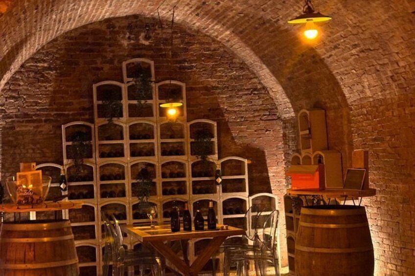 Une cave avec des barriques en bois, un meuble à vin et une table avec des chaises. 3