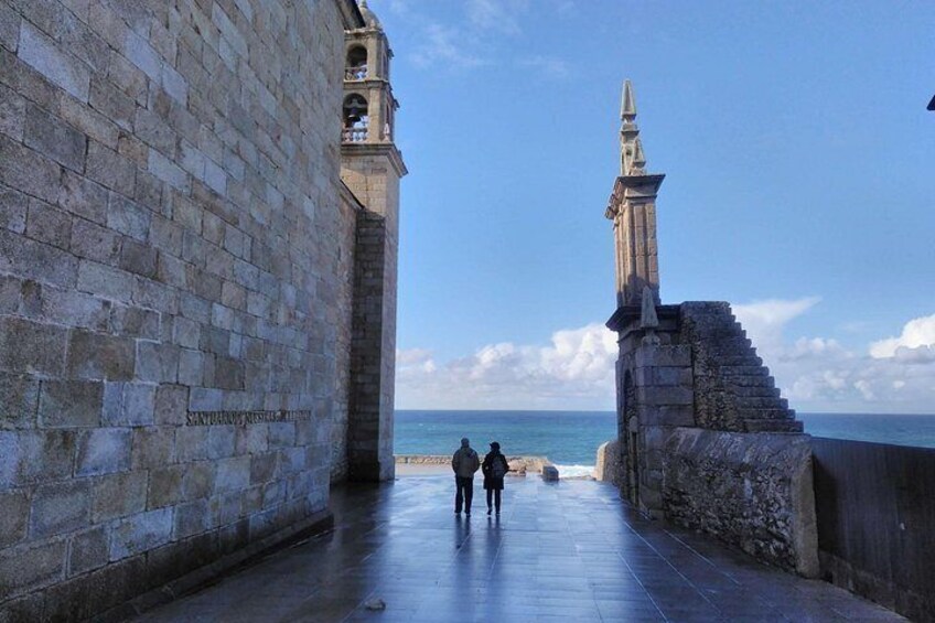 A stone pathway leading to a coastal area with a tower and a statue. 2