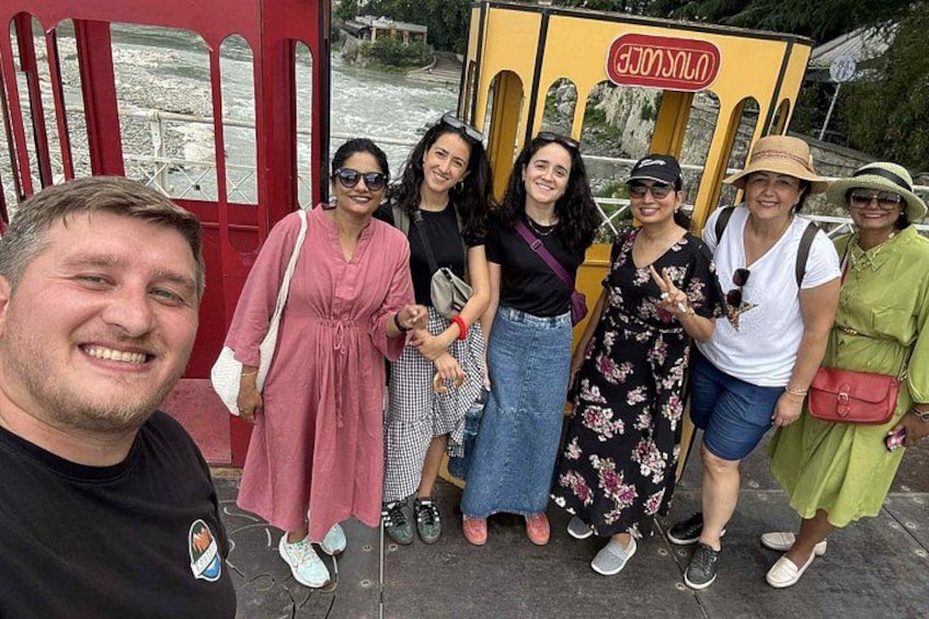 Eine Gruppe von Menschen posiert vor einer gelben Straßenbahn mit dem Schriftzug 'UNLOCKED'. 1