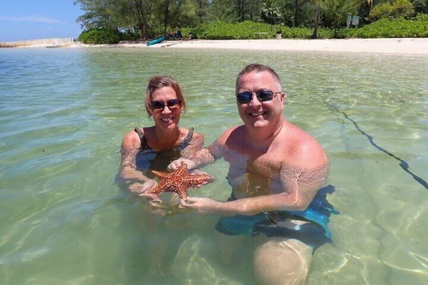 Zwei Personen halten in klarem Wasser einen Seestern. 5