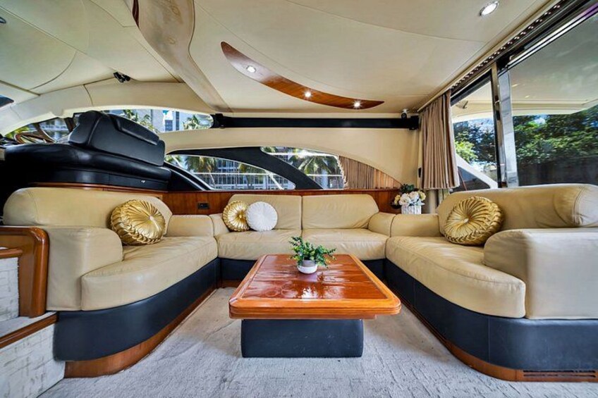 A luxurious yacht interior with a curved seating area, a central wooden coffee table, and a potted plant. 4