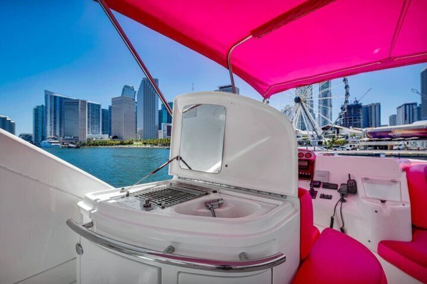A boat with a white interior and a pink canopy, docked near a city skyline with modern buildings and a Ferris wheel. 4