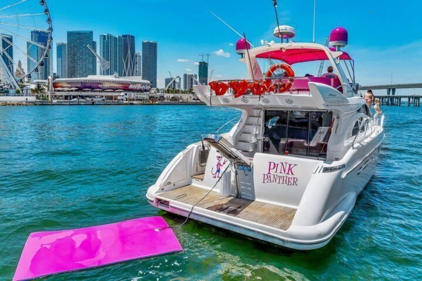 A boat named 'PINK PANTHER' docked at a marina with a Ferris wheel and skyscrapers in the background. 3