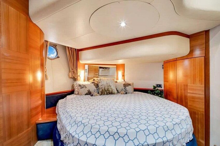 A bedroom with a large bed, wooden walls, a round ceiling light, and a window with curtains. 3