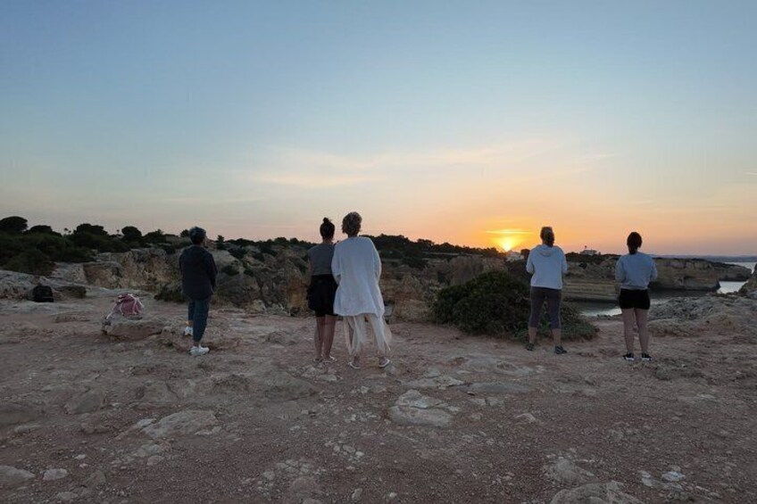 Personas de pie sobre terreno rocoso al atardecer. 5