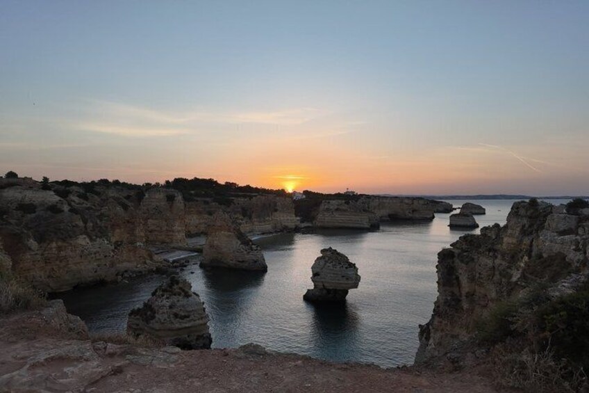 Un atardecer sobre un paisaje costero con formaciones rocosas y agua tranquila. 2