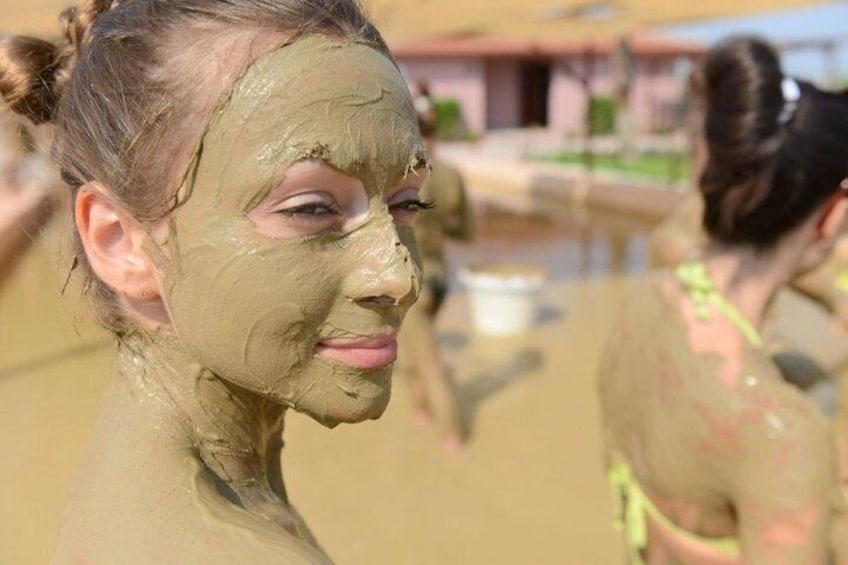 A person covered in mud, with a building and a pool in the background. 1