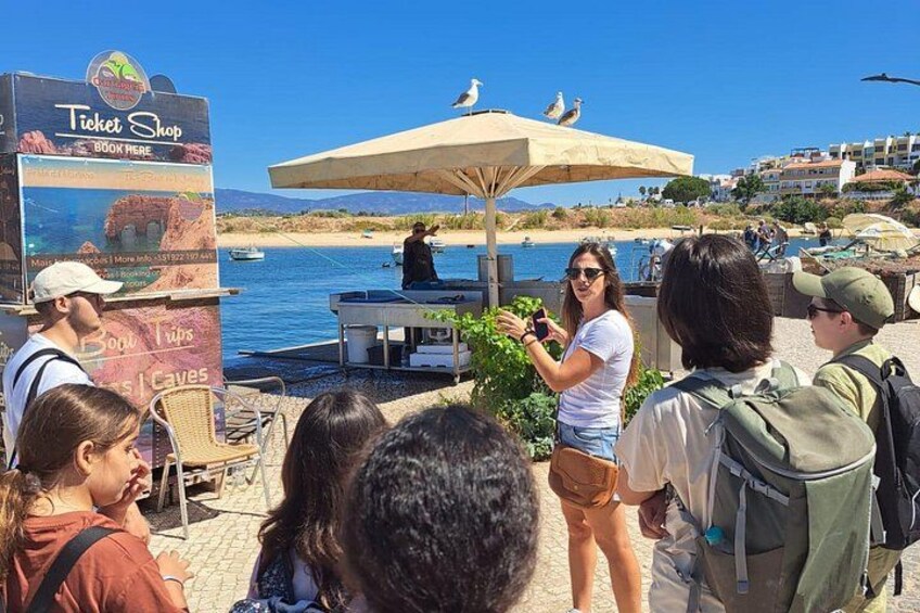 A ticket shop with a signboard, a person taking a photo, and a beach in the background. 4