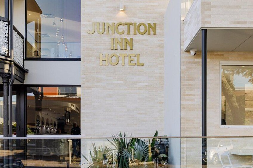 Een hotelentree met een bord waarop 'JUNCTION INN HOTEL' staat en een moderne gevel. 1