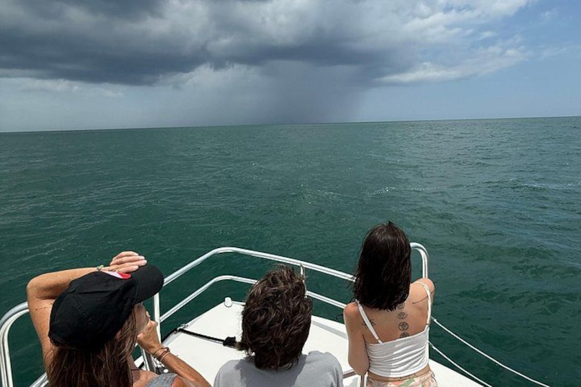 Three people on a boat with a view of the ocean and stormy sky. 2