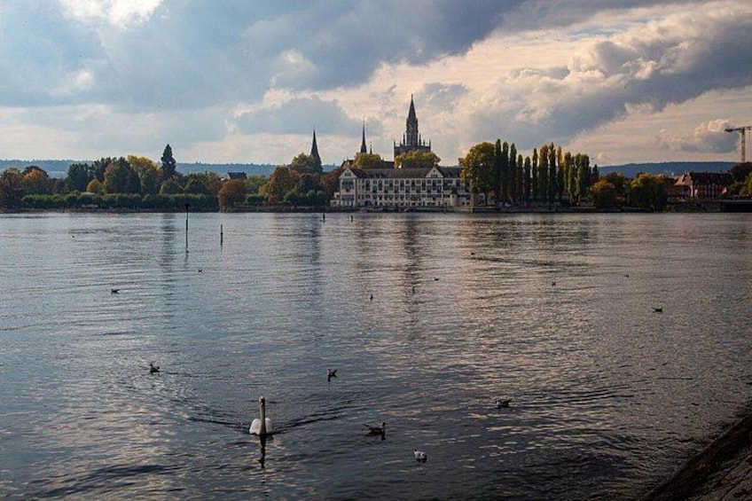 Un río tranquilo con cisnes, una iglesia y una aguja al fondo. 5