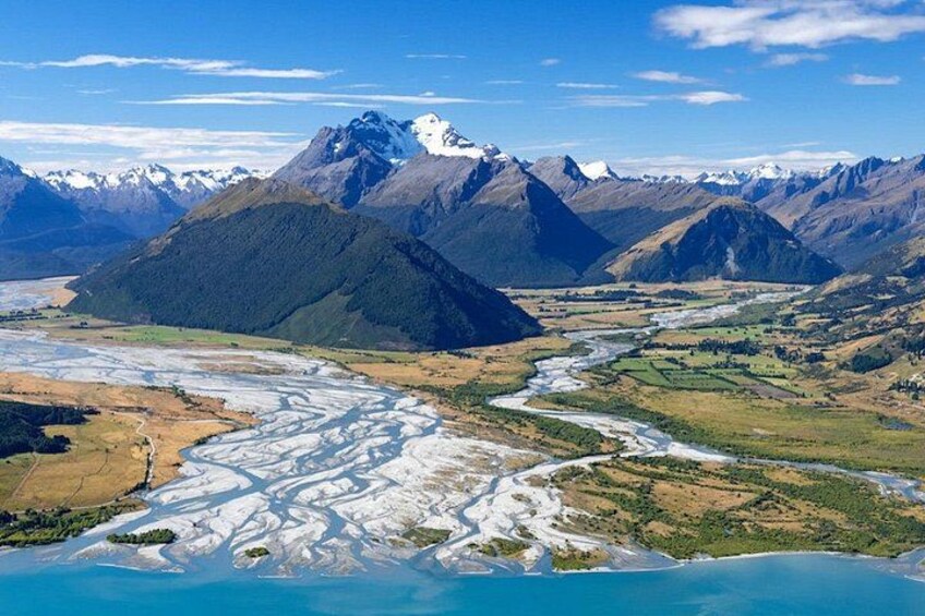 A river winding through a mountainous landscape with snow-capped peaks in the background. 2